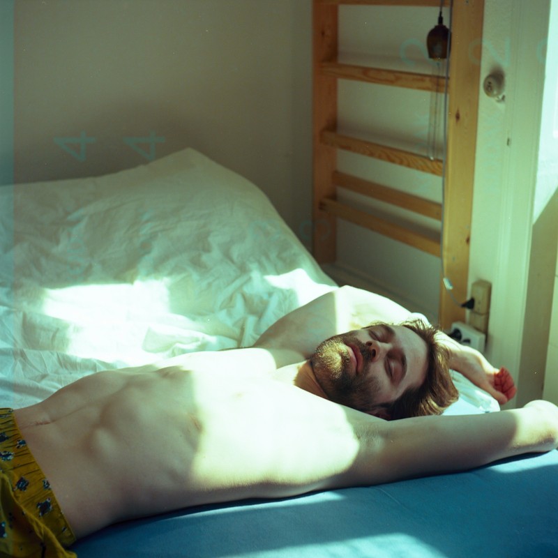Person sleeping deeply in a dark, cool bedroom with blackout curtains and a sleep mask