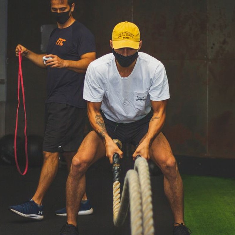 Two men engaged in a dynamic workout using battle ropes and resistance bands indoors.