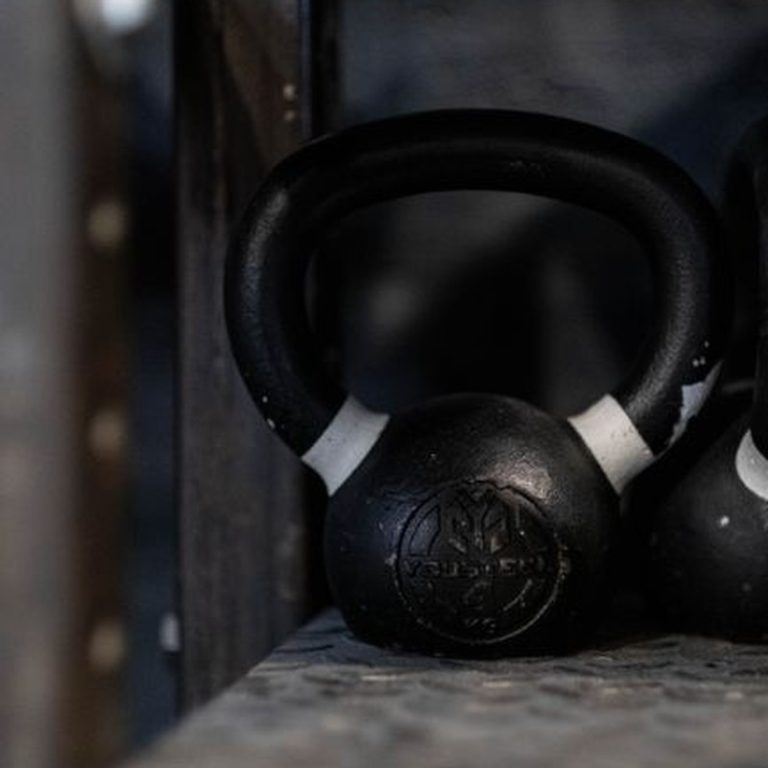 Black kettlebell on a gym shelf, ideal for weightlifting and strength training imagery.