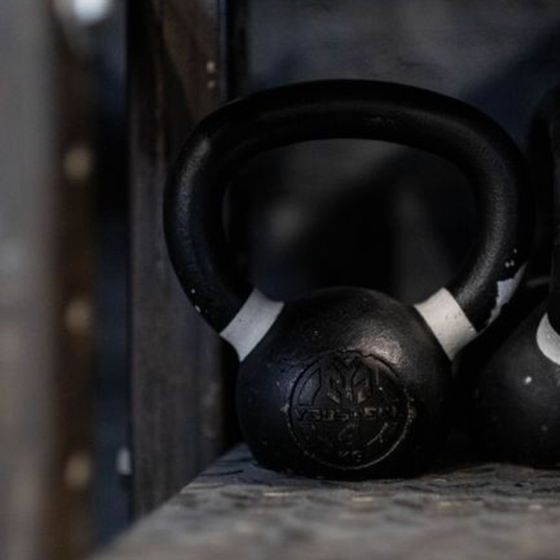 Black kettlebell on a gym shelf, ideal for weightlifting and strength training imagery.