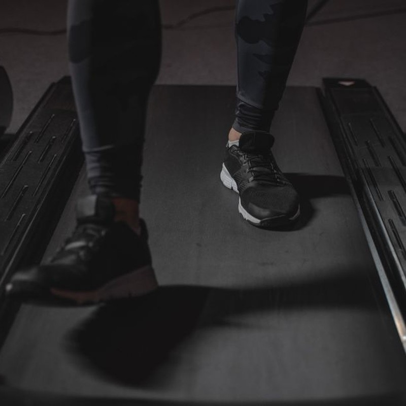 Feet running on treadmill in gym. Focus on black sneakers. Fitness and cardio exercise concept.