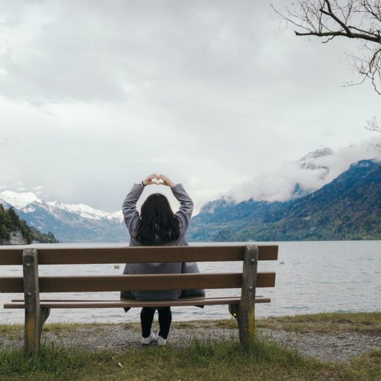 Woman sitting on a bench enjoying nature at Lake Interlaken, Switzerland.