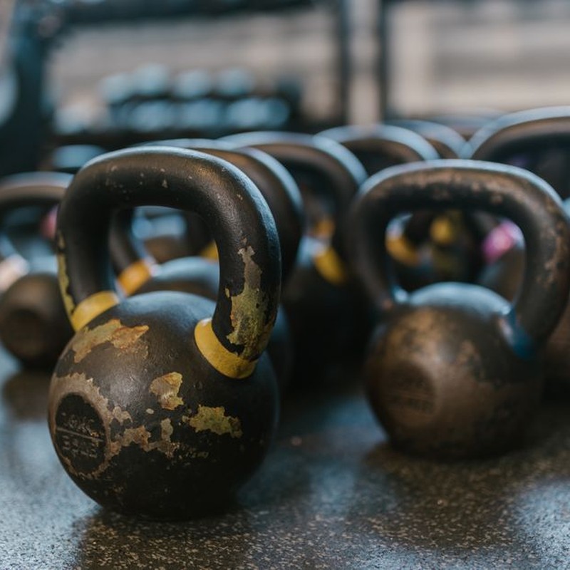 A collection of black kettlebells on a textured gym floor, perfect for fitness enthusiasts.