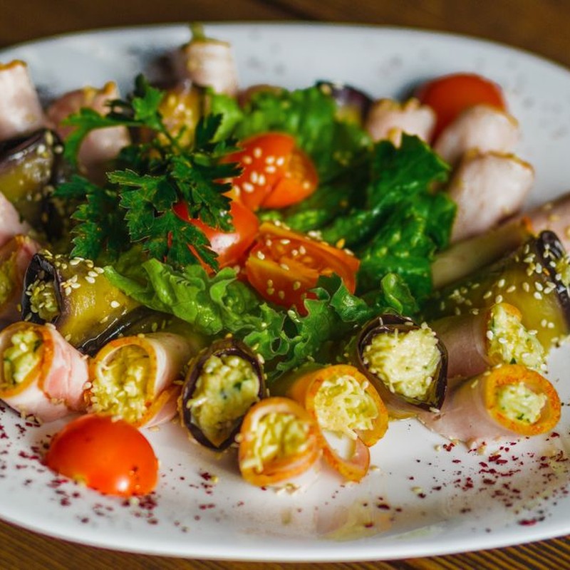 Colorful vegetable and ham rolls garnished with cherry tomatoes and lettuce, perfect for a healthy meal.