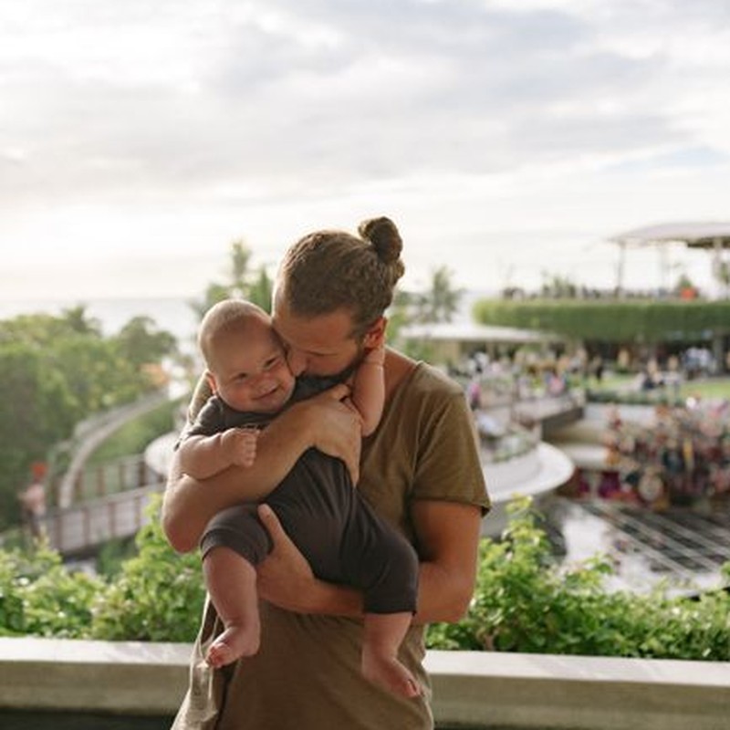 A joyful dad holding his baby with love and warmth outdoors, showcasing fatherhood.