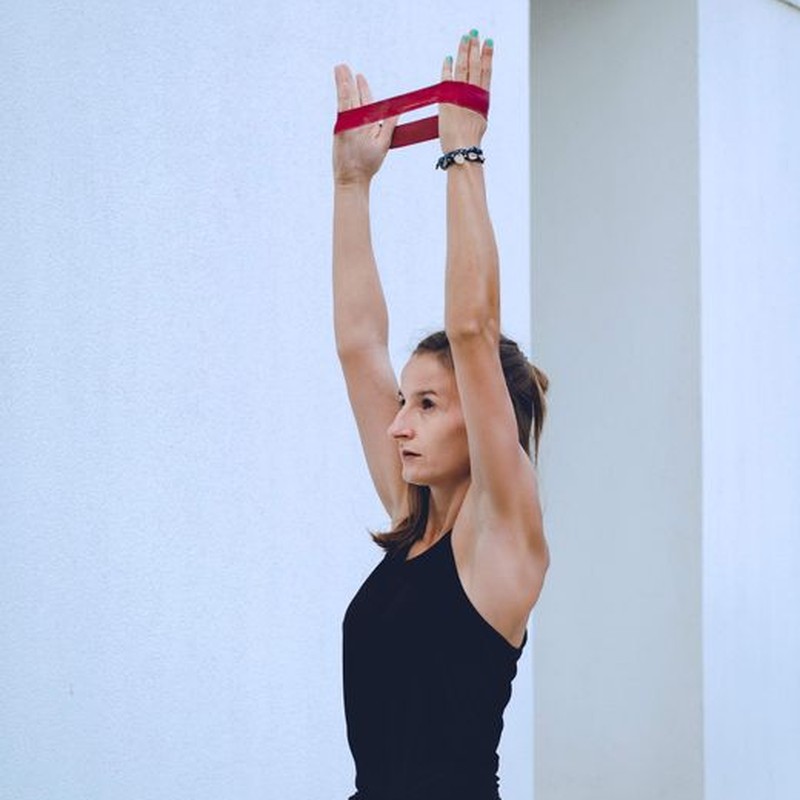 Woman in activewear using a resistance band for fitness exercise outside.