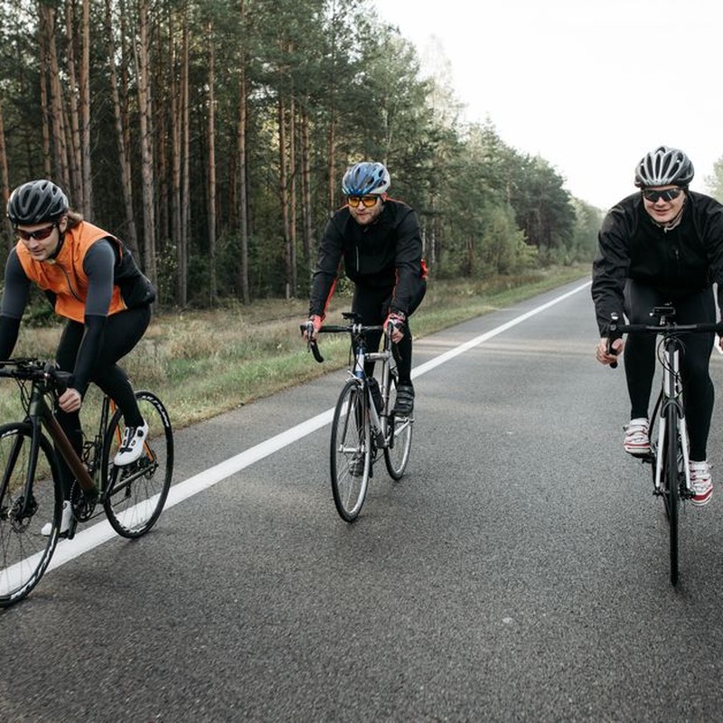 Three cyclists are enjoying a ride on a scenic forest road during the day.