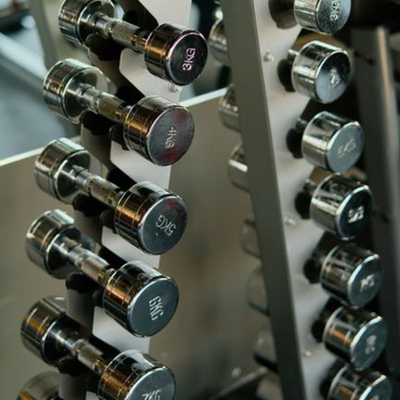 Close-up of chrome dumbbells neatly organized on a rack in a modern gym.