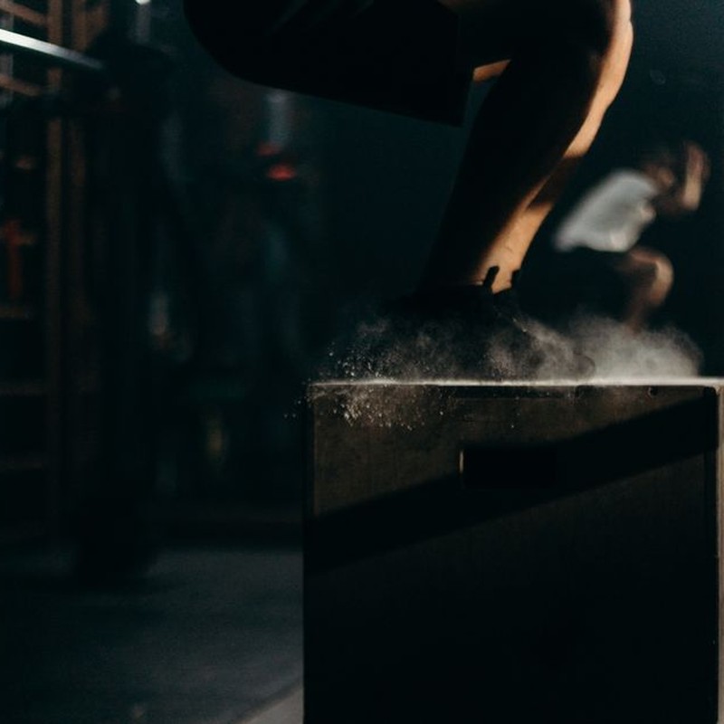A dynamic gym scene with a person performing box jumps, showcasing strength training indoors.