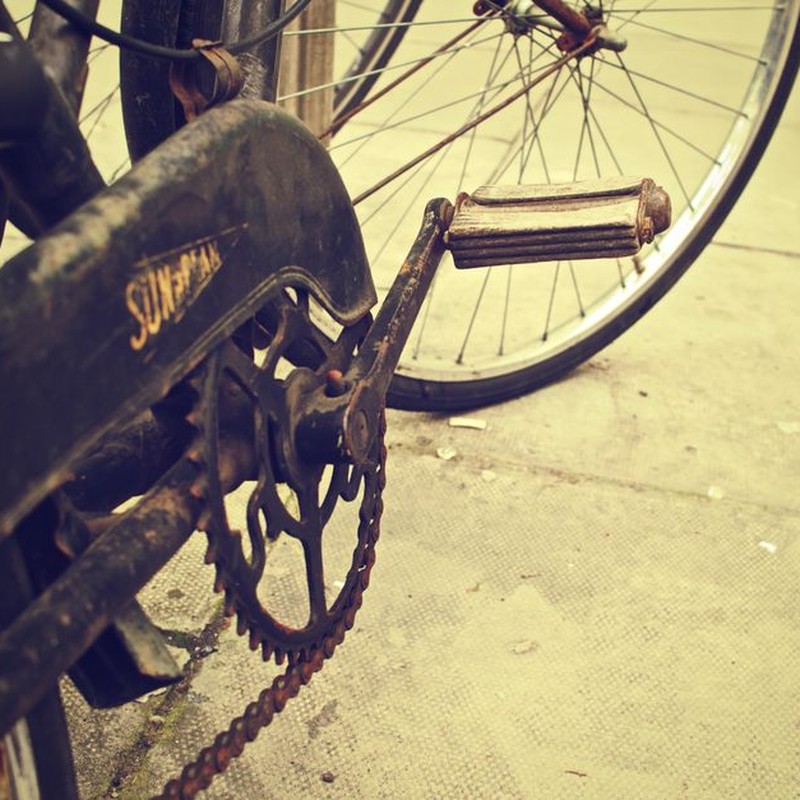 A detailed shot of an old rusty bicycle chain and pedal on a vintage bike, conveying a nostalgic feel.