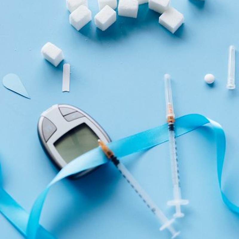 Flat lay of diabetes awareness items including glucometer and insulin syringes.