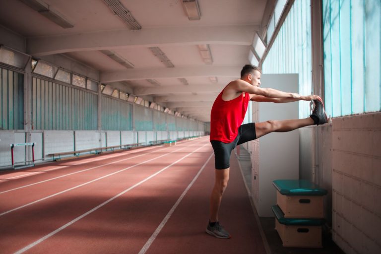 Athlete stretching hamstring on indoor track