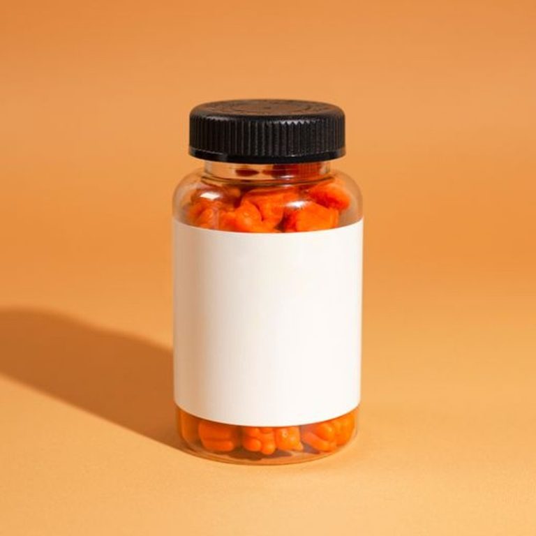 A clear bottle filled with orange gummy vitamins against an orange background.