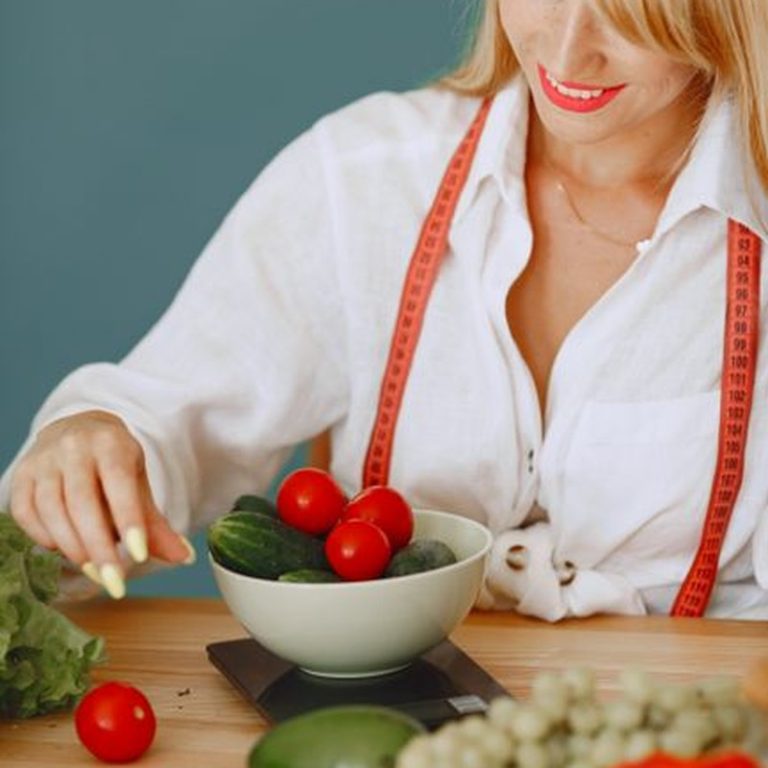 A nutritionist measuring fresh vegetables on kitchen scales for a healthy lifestyle.