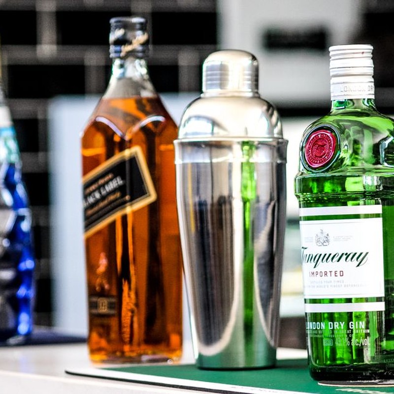 A selection of liquor bottles including gin, whiskey, and a cocktail shaker on display.