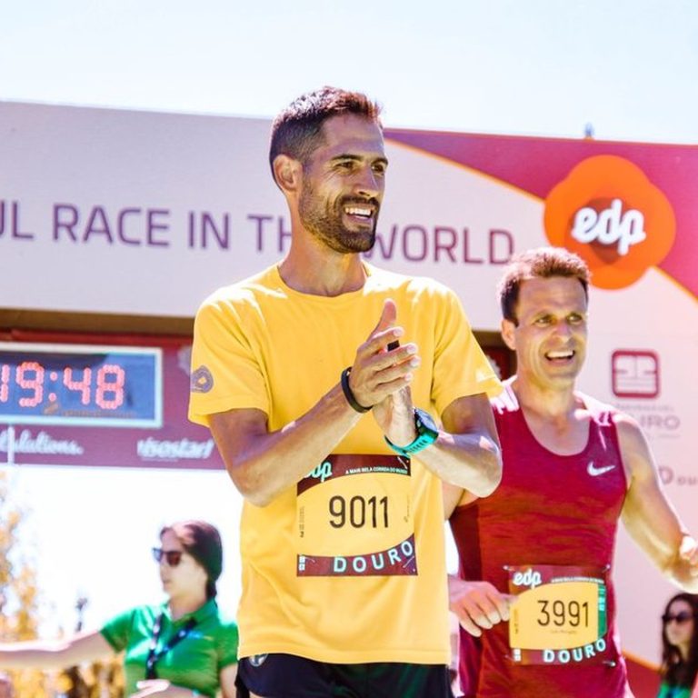 Marathon runners celebrating their successful finish at a race event in bright daylight.