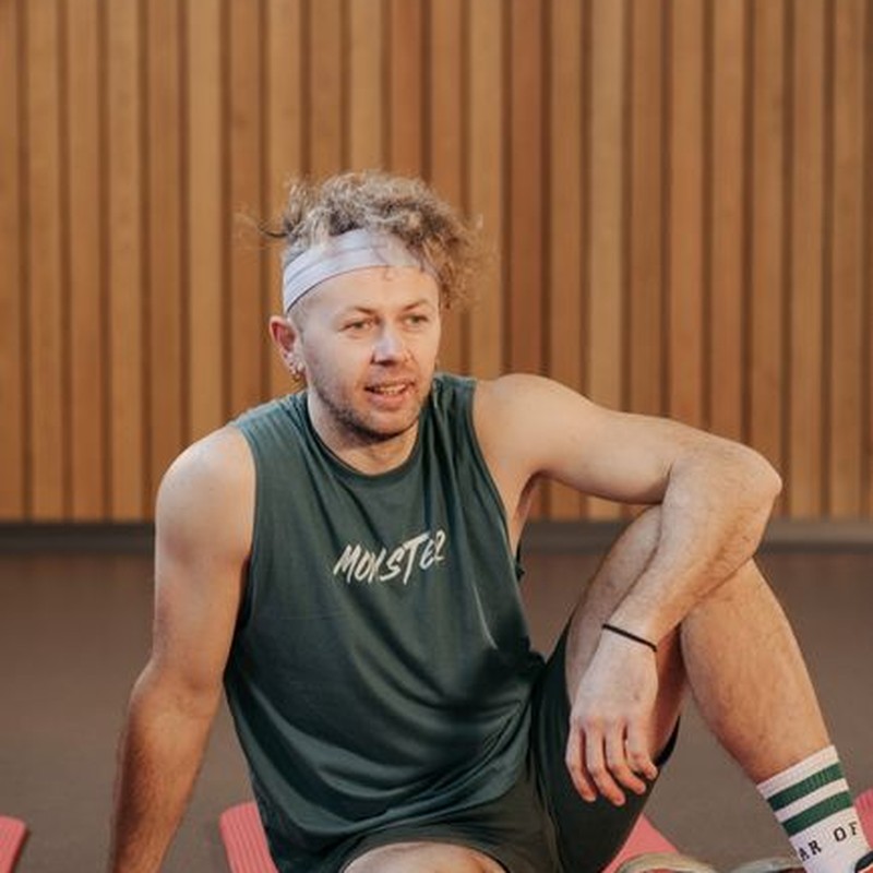 Man in gym attire sits on a yoga mat, showcasing fitness and relaxation.