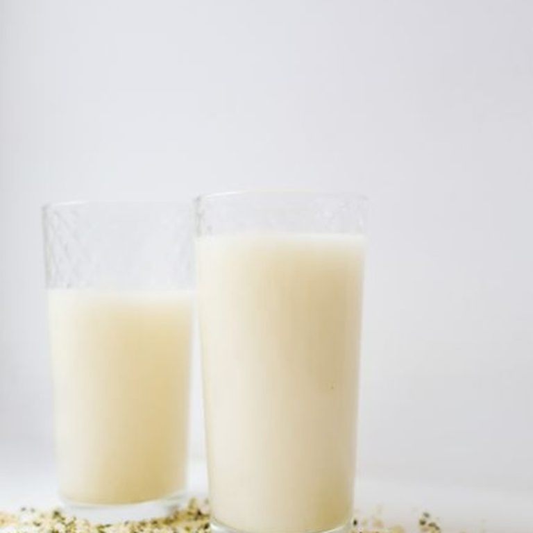 Fresh hemp milk with scattered seeds in a minimalist setting.