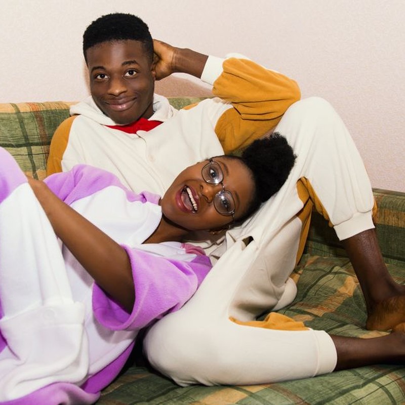 Joyful couple lounging on a couch wearing cozy and colorful pajamas indoors.