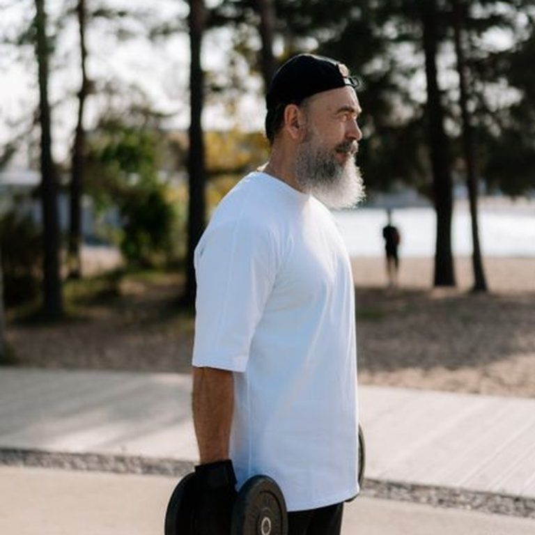 Man exercising outdoors with dumbbells, showcasing strength and fitness.