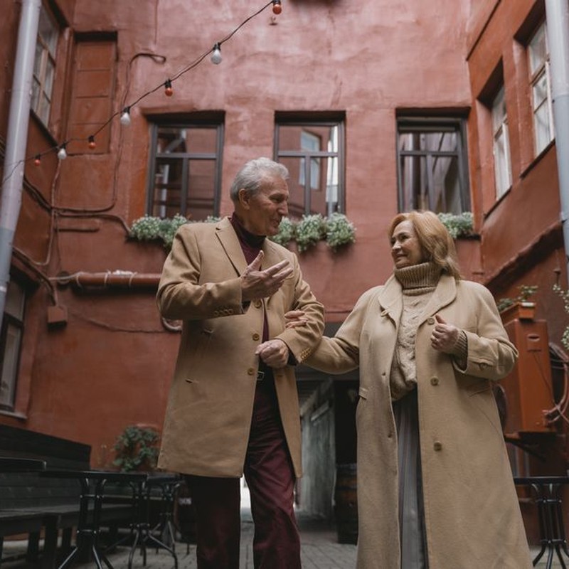 A joyous elderly couple walking hand in hand, sharing a moment in an urban setting.