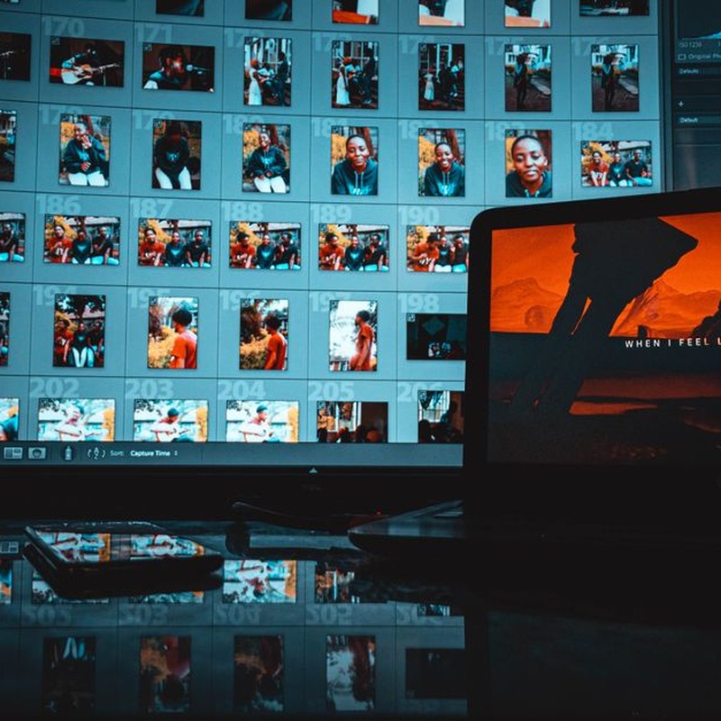 A modern creative workspace featuring a laptop and monitor displaying digital images and editing software.