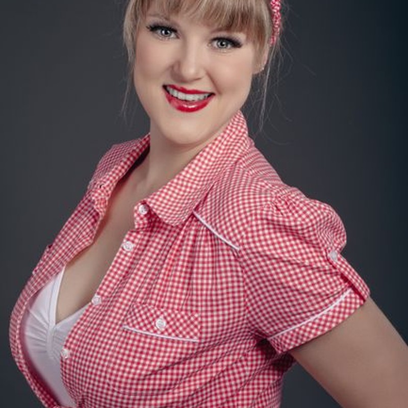 Cheerful woman in red checkered shirt and headband, vintage style portrait.
