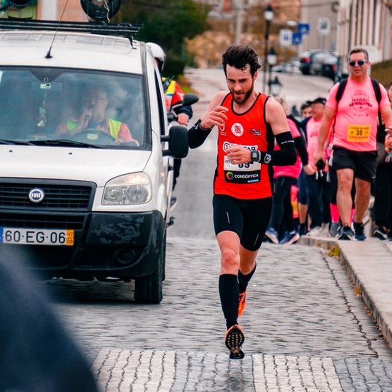 Male athlete running in urban marathon with supportive crowd.