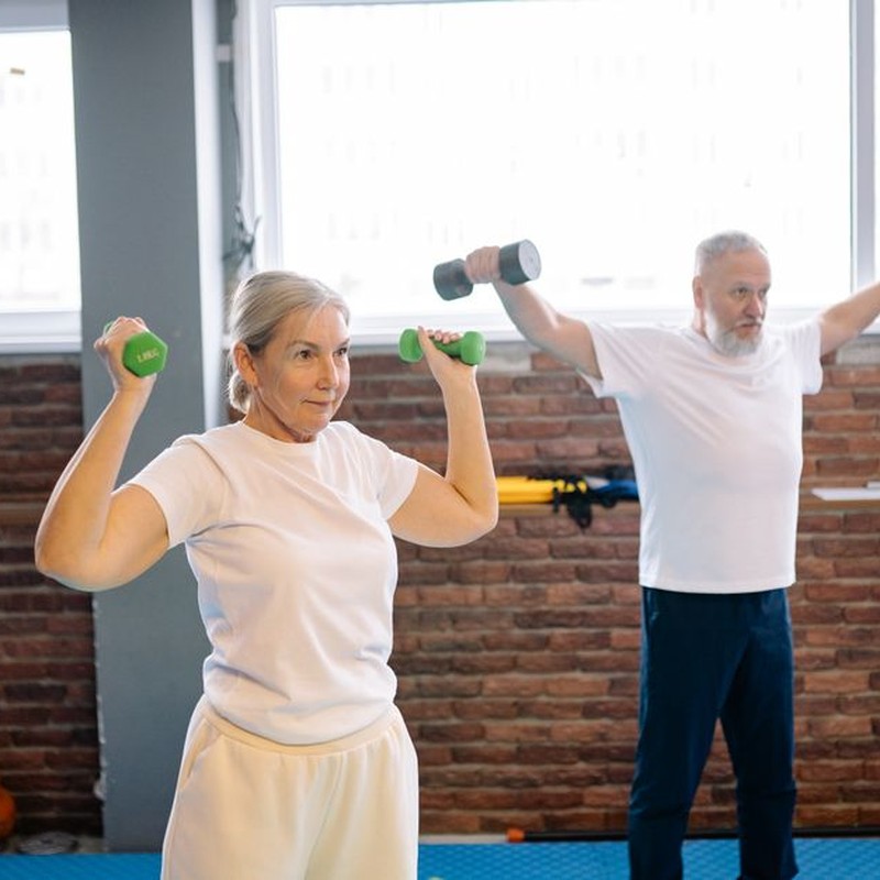 Elderly man and woman workout with dumbbells promoting healthy lifestyle and fitness.