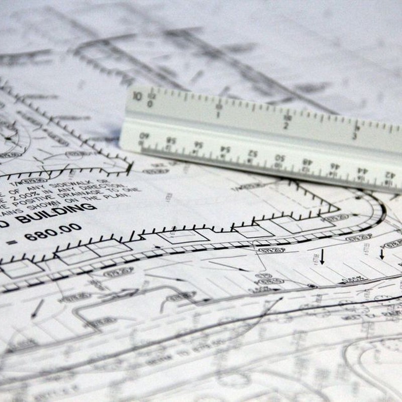 Detailed close-up of architectural blueprints with scale ruler, showing building plans and measurements.