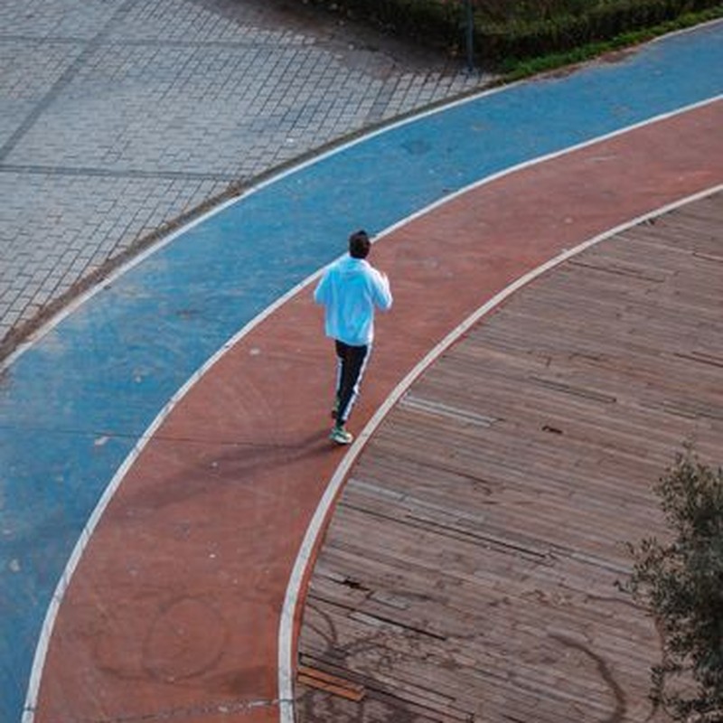 A runner in sportswear jogs on a colorful track, viewed from above. Vibrant and dynamic.