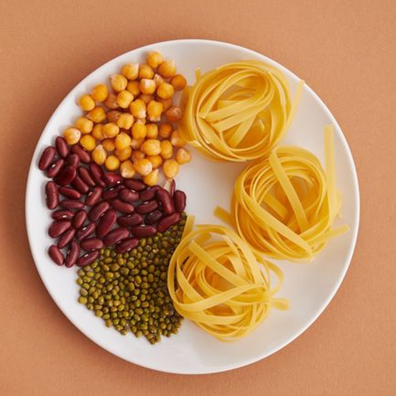 Overhead shot of tagliatelle pasta, chickpeas, kidney beans, and green lentils on a plate.