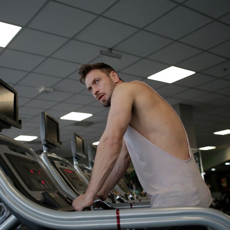 A focused man exercising on a treadmill in a modern gym setting, showcasing dedication and fitness.
