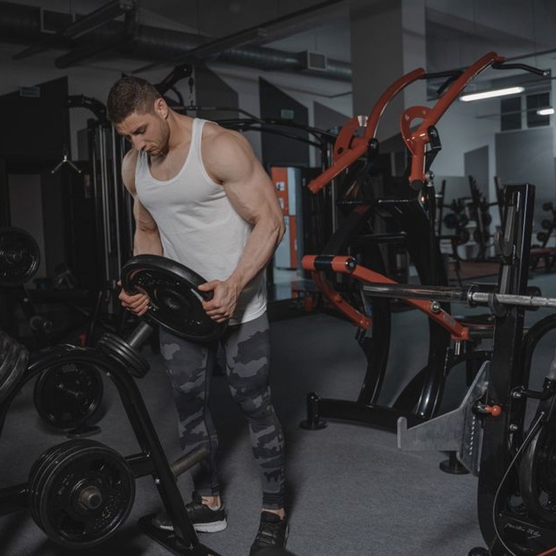 Muscular man lifting weights in a well-equipped gym for strength training.