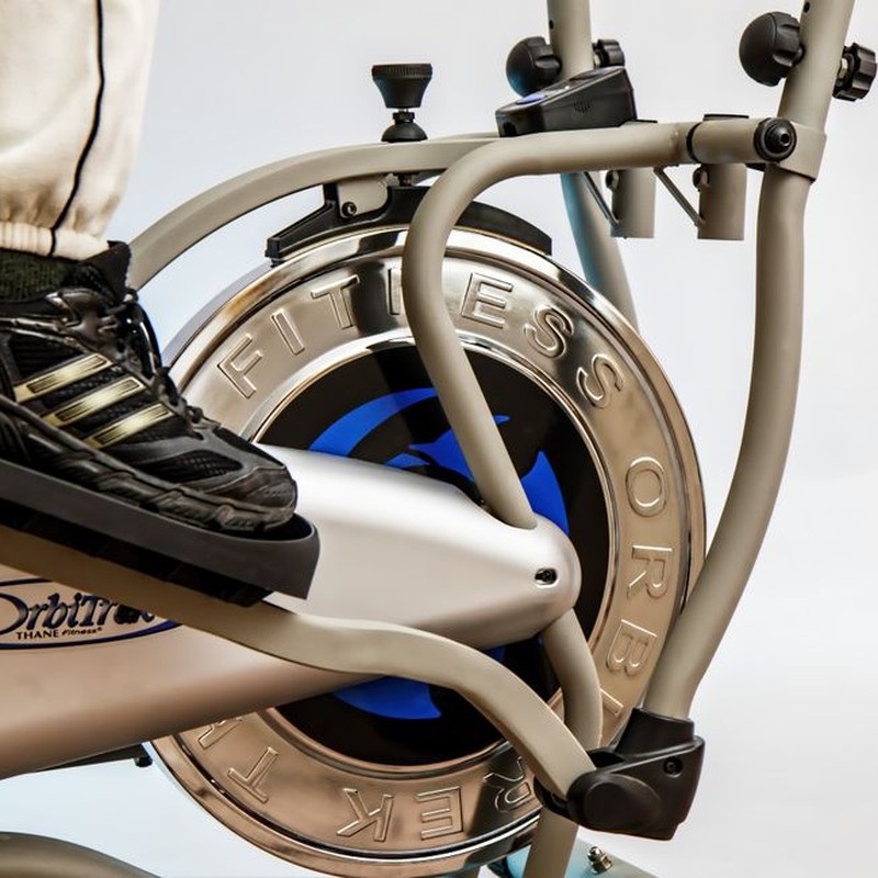 Foot on pedal of elliptical trainer showcasing fitness equipment and footwear close-up.
