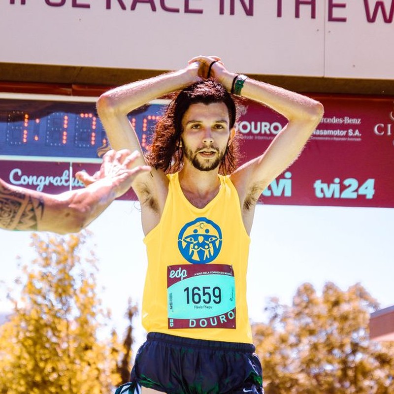 Exhausted marathon runner crossing the finish line triumphantly under sunny skies.