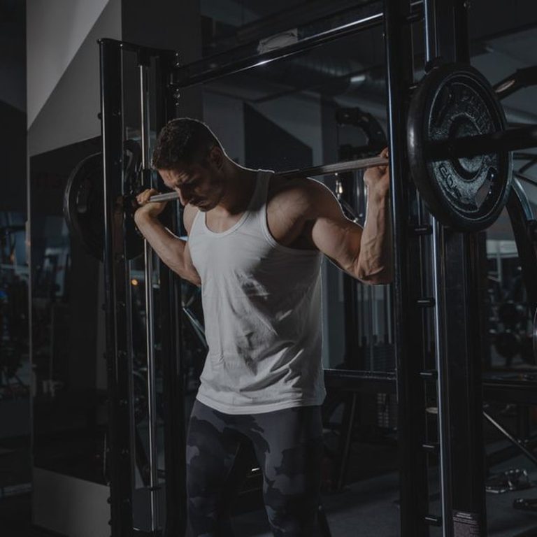 Athletic man in activewear lifting weights at the gym, showcasing strength.