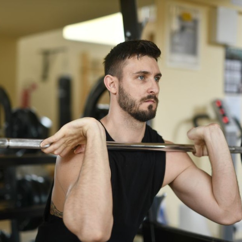 A determined man lifting a barbell in a gym, focusing on strength and fitness.
