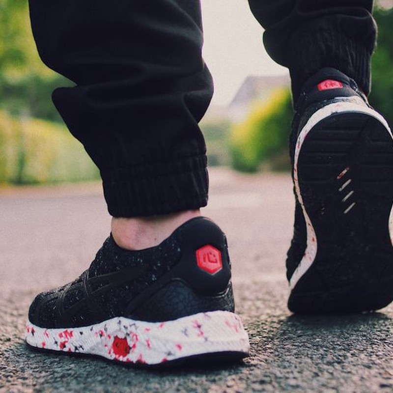 Close-up of a person walking with stylish sneakers on a bright street.