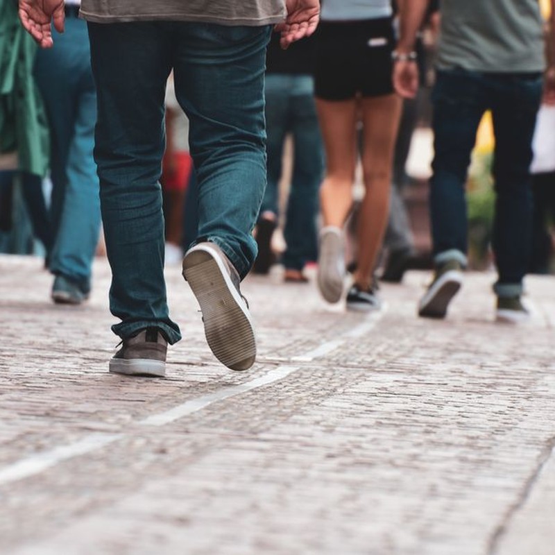 A diverse group of individuals walking on a cobblestone street, showcasing urban daily life.