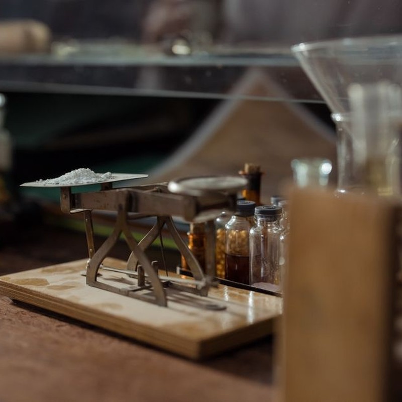 Close-up of an antique apothecary scale with pill bottles in a vintage pharmacy setting.