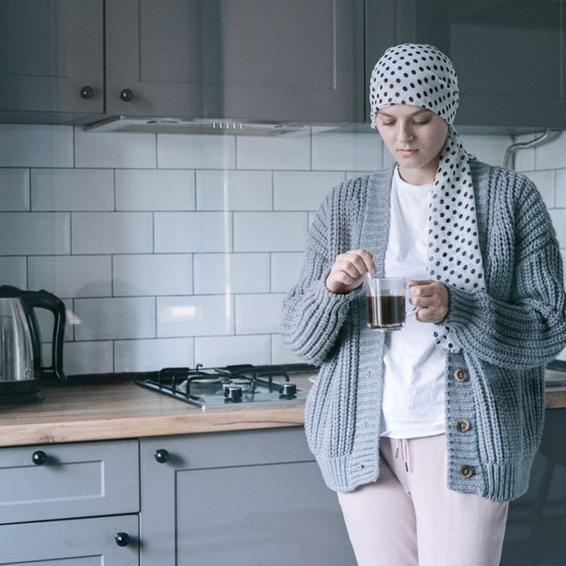 Woman in headscarf holding a cup of coffee in a cozy kitchen, symbolizing hope and recovery.