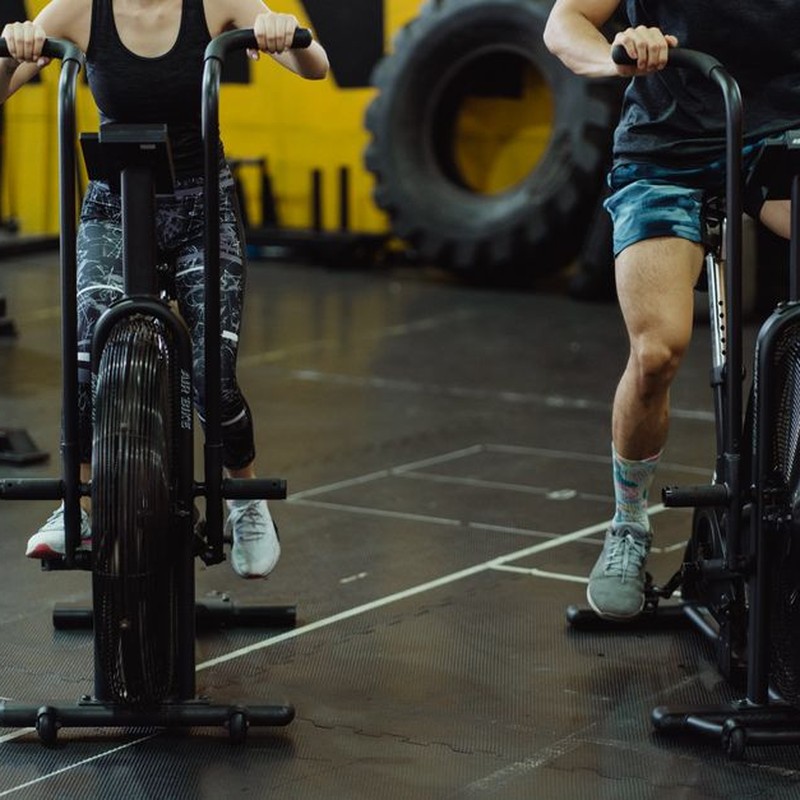 Two people exercising on stationary bikes at a modern gym.