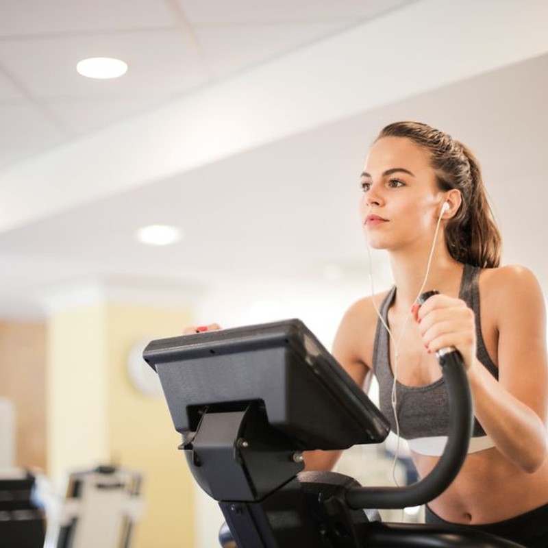 Woman in a gym focused on cardio exercise using elliptical machine. Healthy lifestyle and fitness concept.