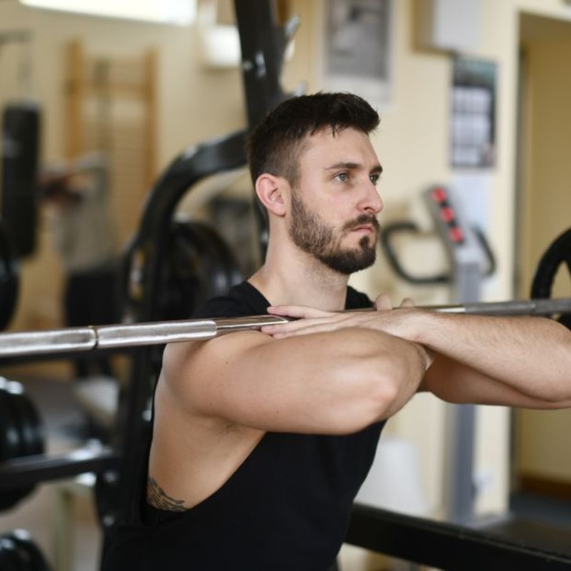 A focused man lifting weights indoors showcasing strength and concentration.