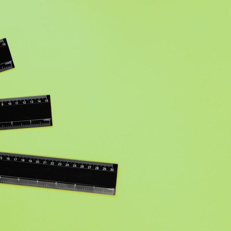 Three black rulers arranged on a vibrant green background, ideal for educational or design contexts.