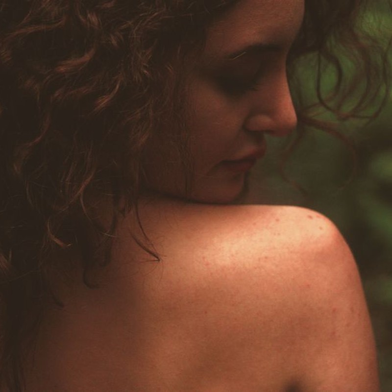 Artistic portrait of a woman with curly hair, capturing natural beauty and tranquility.