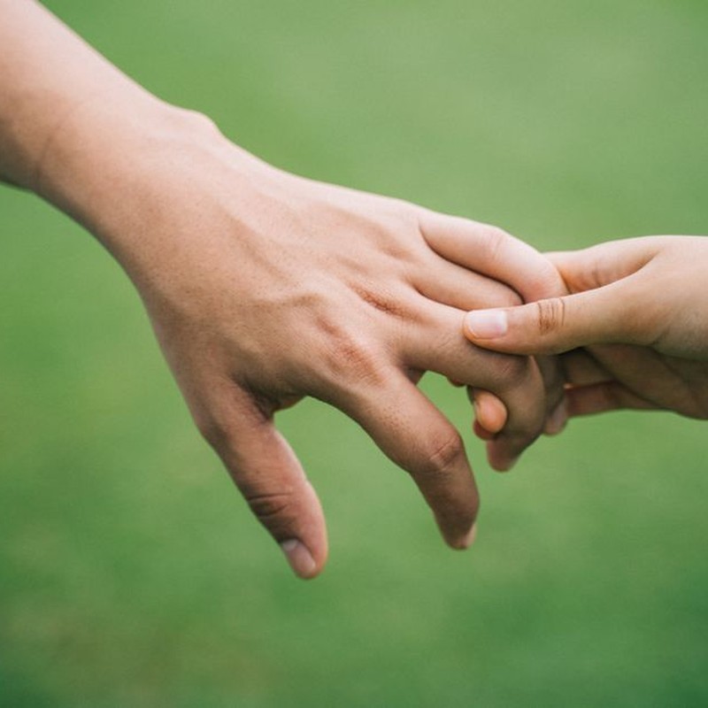 Two hands reaching out and gently touching, symbolizing connection and support.