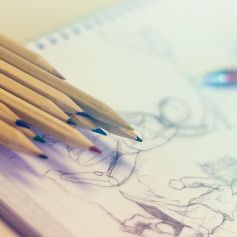 Close-up of colored pencils on sketch-filled notepad, perfect for creativity concepts.