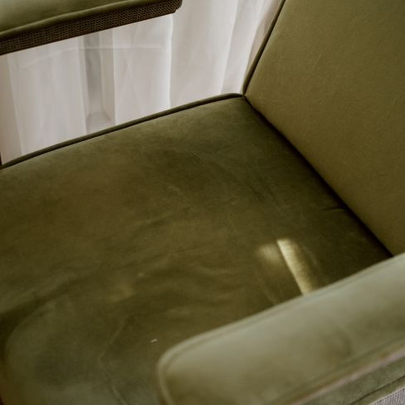 A stylish green armchair positioned by a window, capturing serene indoor lighting and sophisticated design.